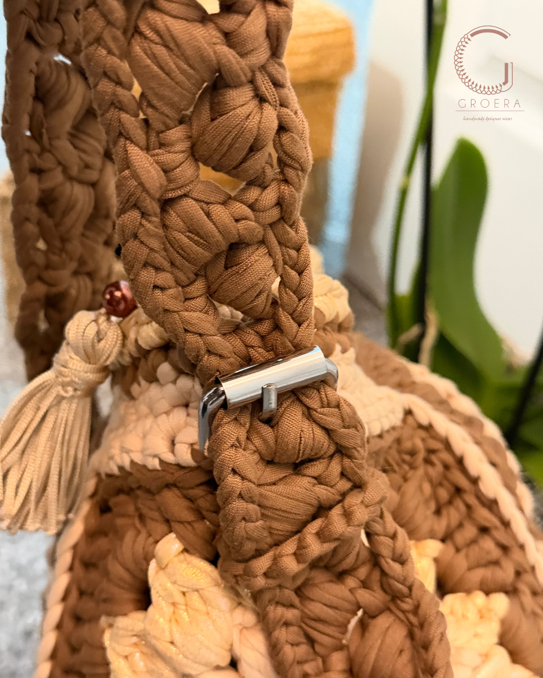 Close-up of a braided brown leather strap with a metal buckle on a textured surface.