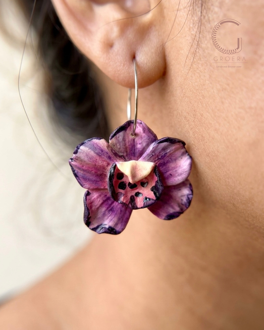 Purple flower-shaped earring worn by a person