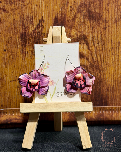 Floral earrings on a display stand with a GroeRA card against a wooden background