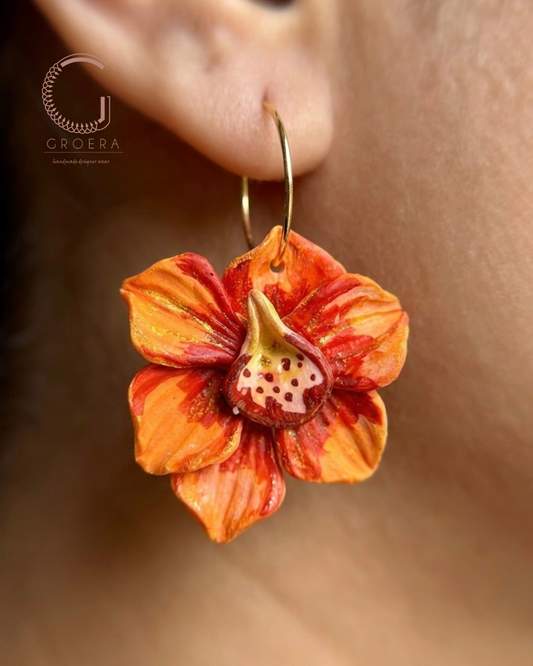 Floral earring worn on an ear with a blurred background