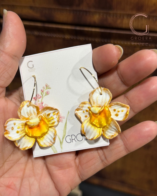 Flower-shaped earrings on a Groera branded card held in a hand.