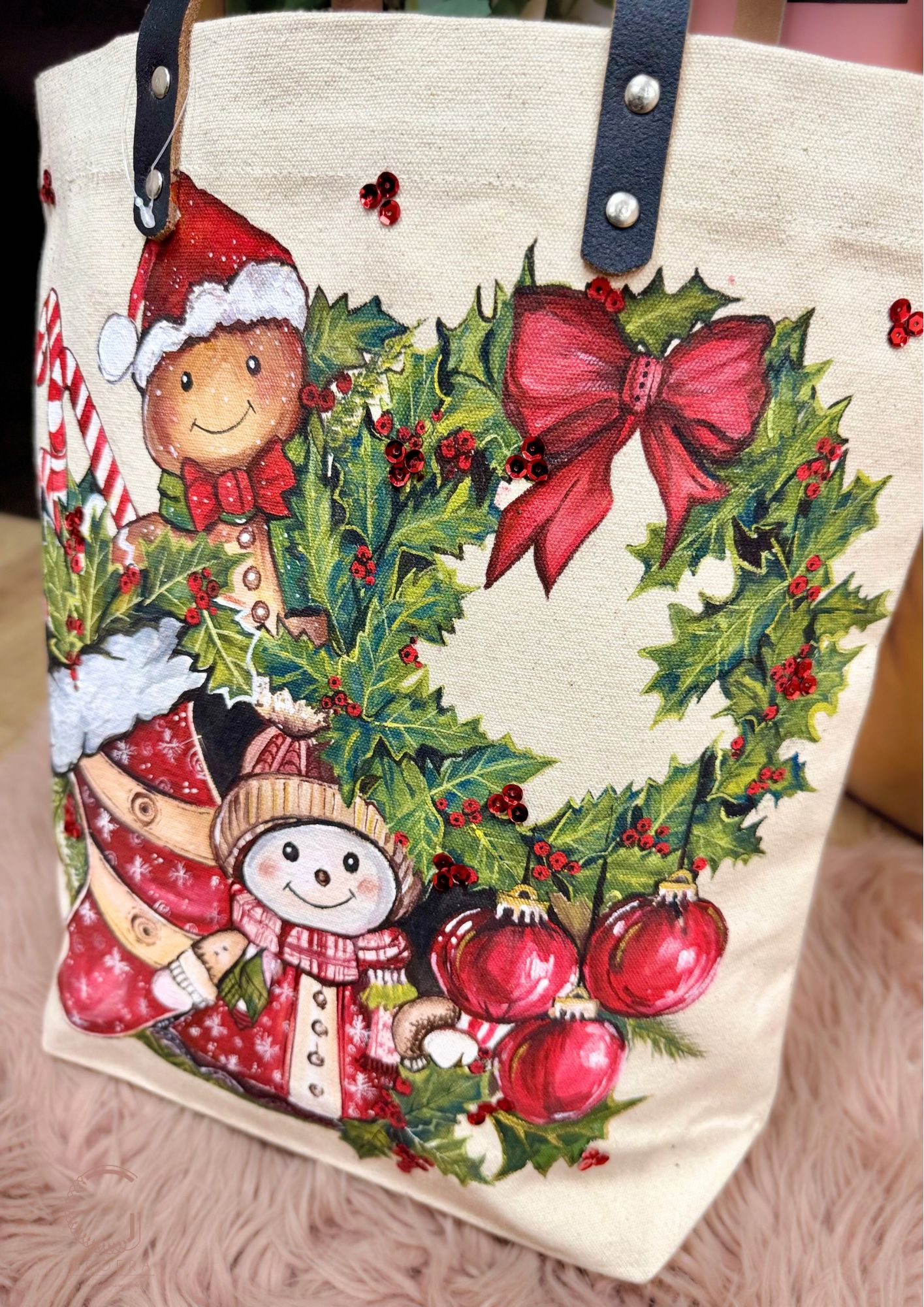 Tote bag with Christmas design featuring snowmen, holly, and red bows on a beige background.
