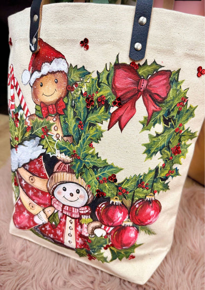 Tote bag with Christmas design featuring snowmen, holly, and red bows on a beige background.