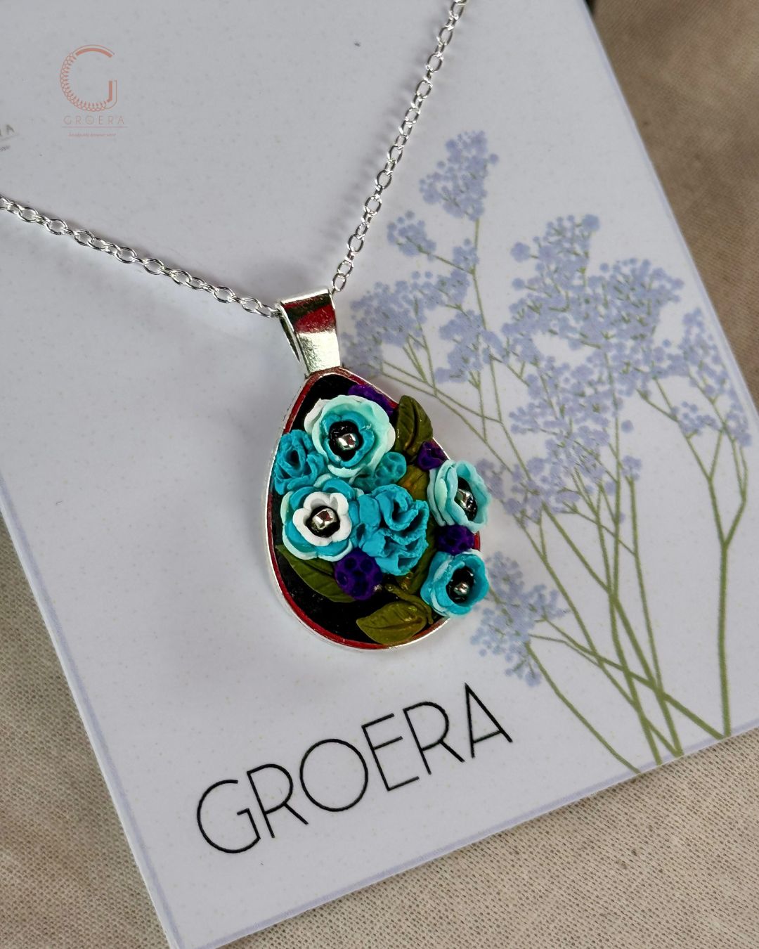 Necklace with floral pendant on a card featuring the brand 'GROERA'.