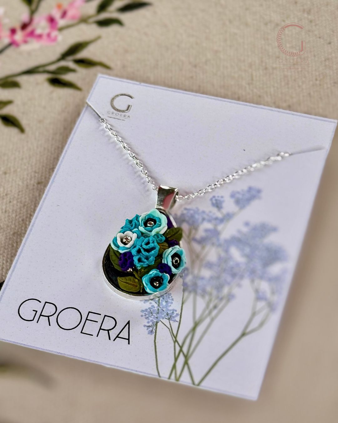 Necklace with floral pendant on a Groera card with flowers in the background