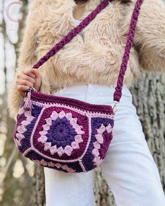 Person holding a purple and pink crochet bag against a natural background