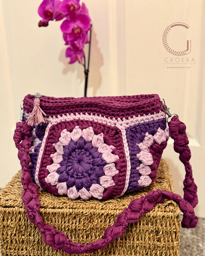 Crocheted handbag with a floral pattern on a textured surface, featuring the brand 'Groera'.